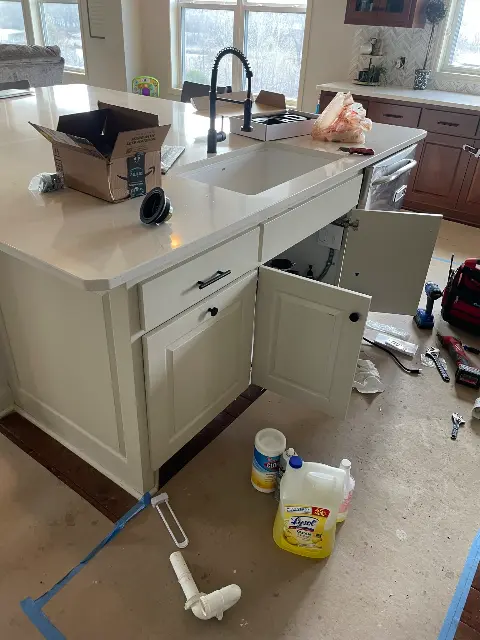 Kitchen renovation in progress with open cabinet and plumbing work